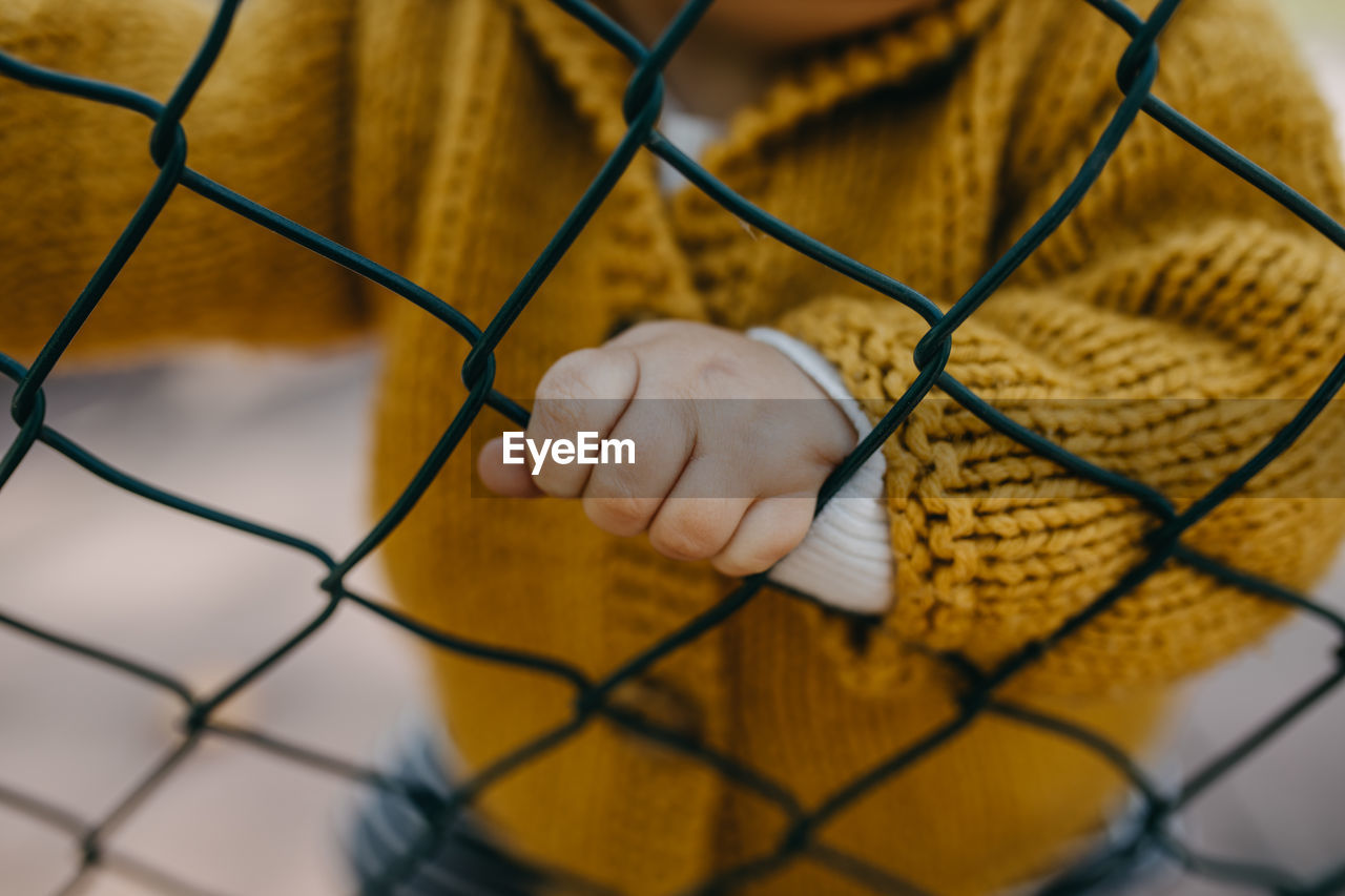 Close-up of toddler hand on chainlink fence