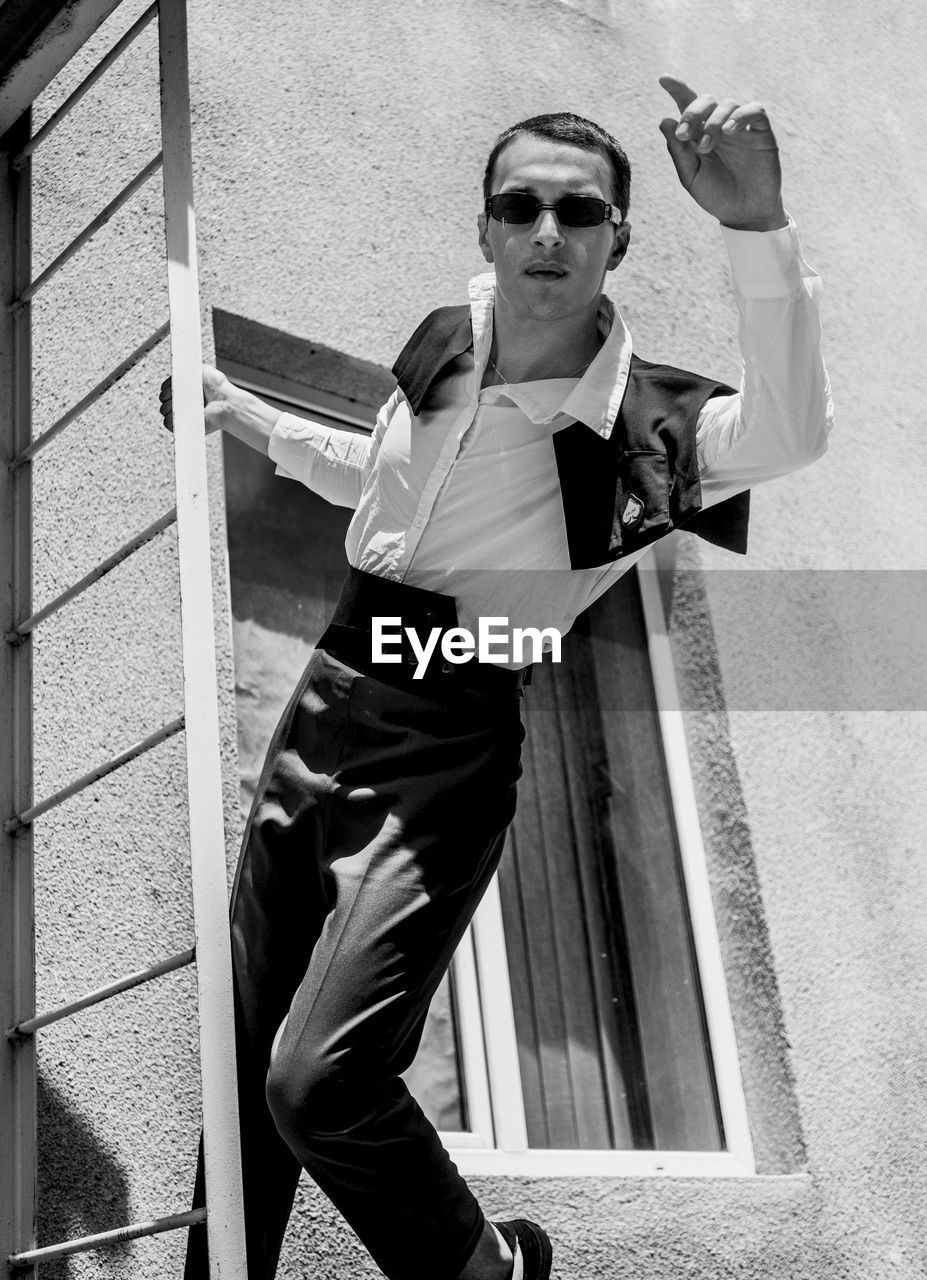 YOUNG MAN WEARING SUNGLASSES STANDING OUTDOORS