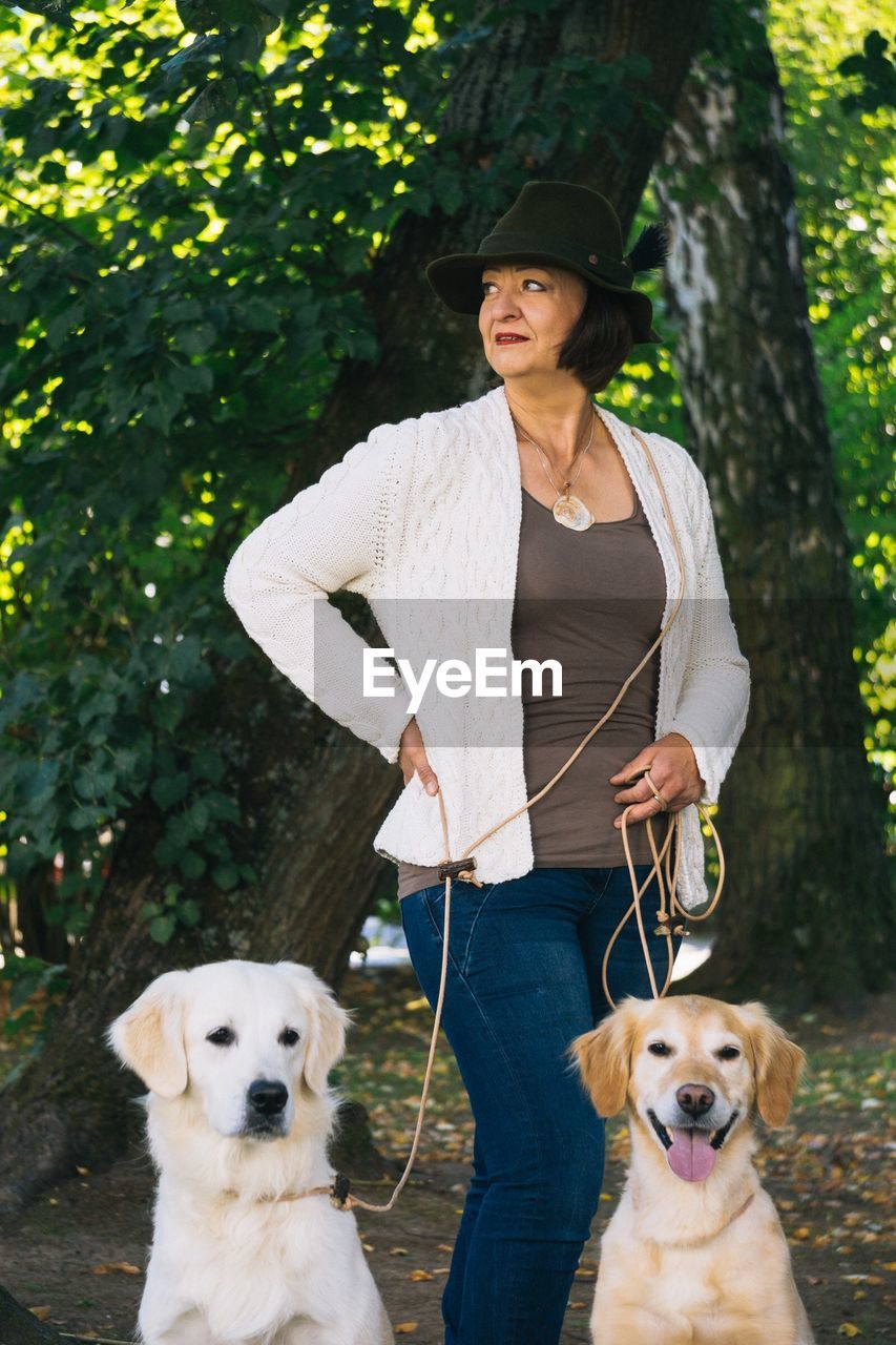 Woman with dogs standing against trees