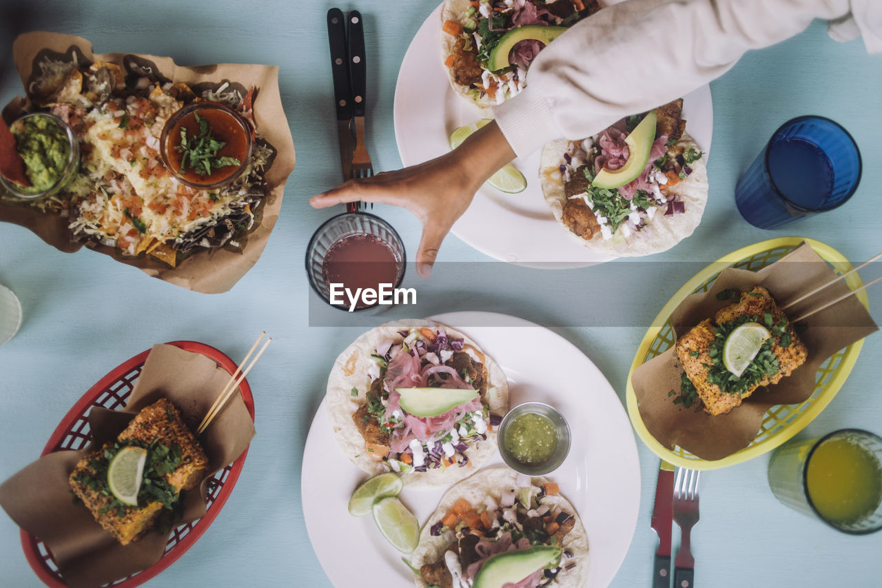 Directly above view of fresh tacos and snacks with drinks arranged on table at restaurant