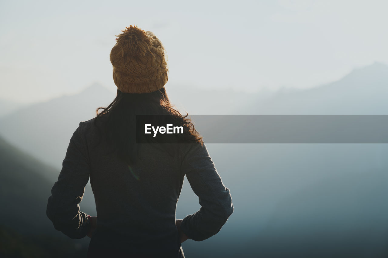 Rear view of man looking at mountains against sky