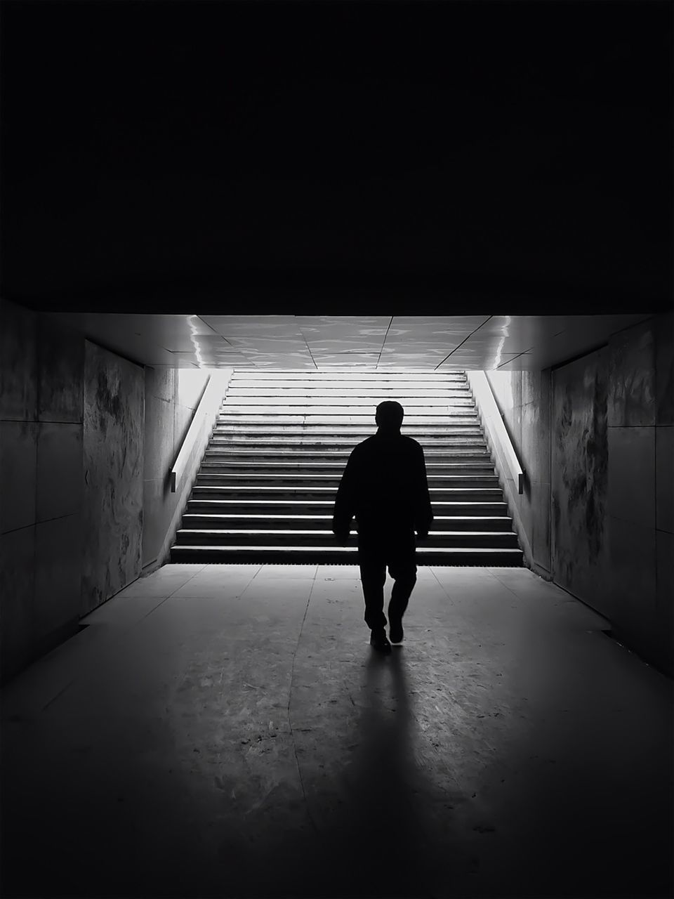 Silhouette of man walking in a tunnel