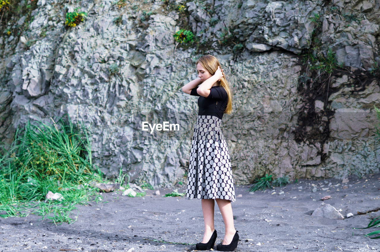 Young woman standing against rock formations at beach