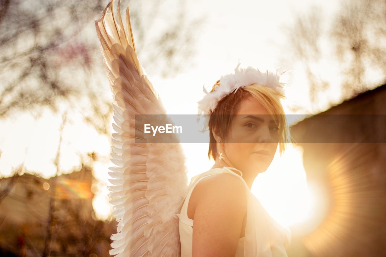 PORTRAIT OF YOUNG WOMAN AGAINST SUNSET SKY