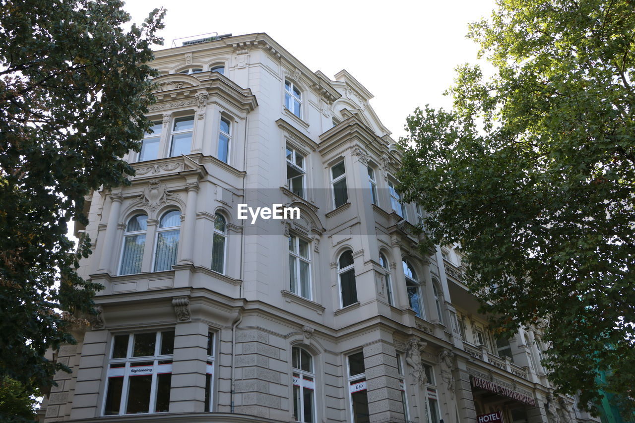 LOW ANGLE VIEW OF BUILDING AND TREES AGAINST SKY