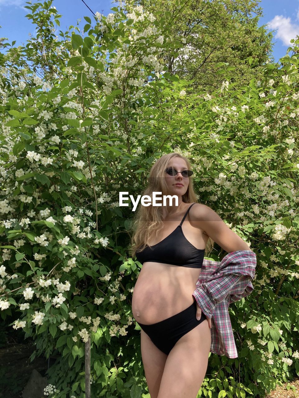 portrait of young woman standing against plants