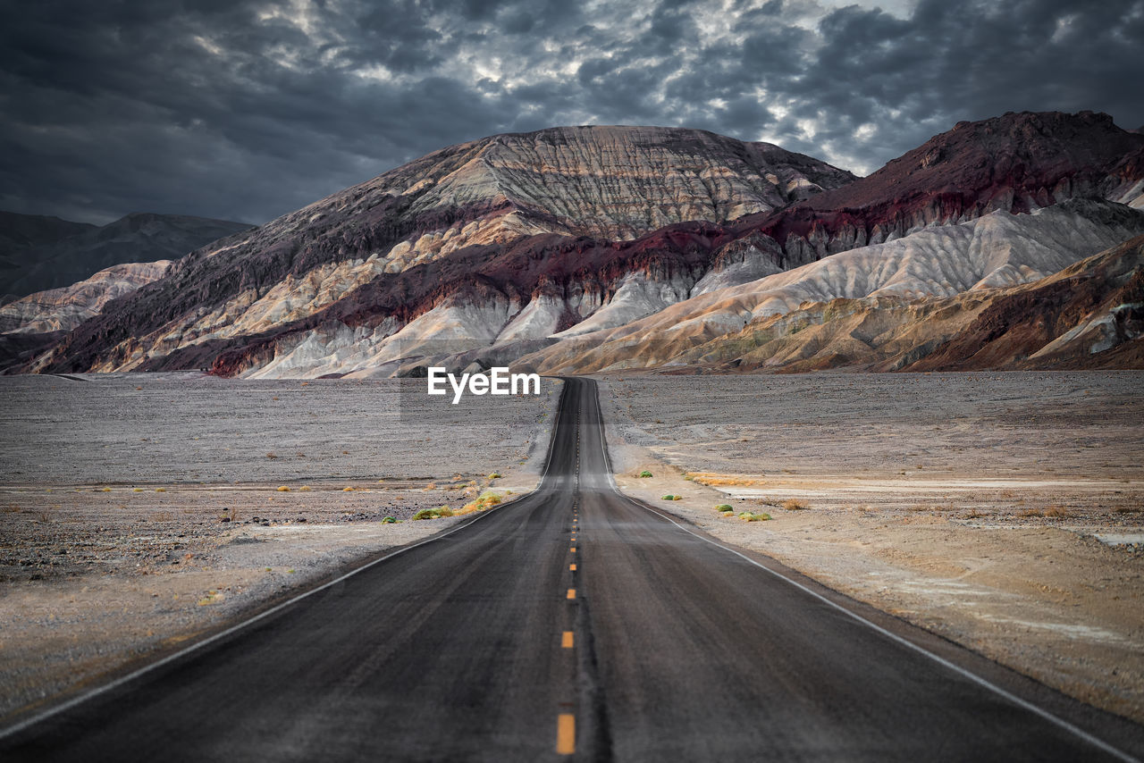 Road leading towards mountains against sky