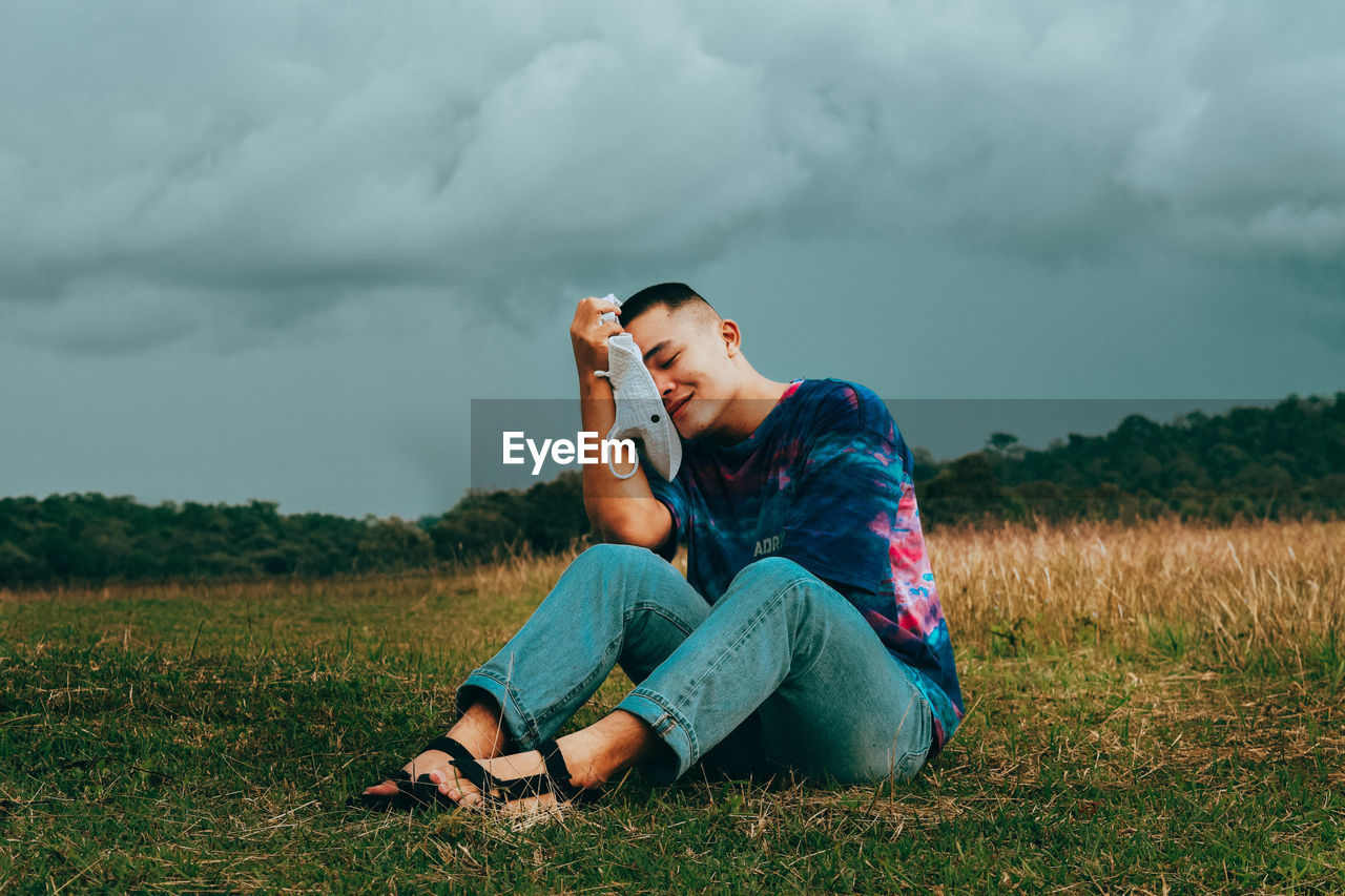 Man using mobile phone while sitting on field