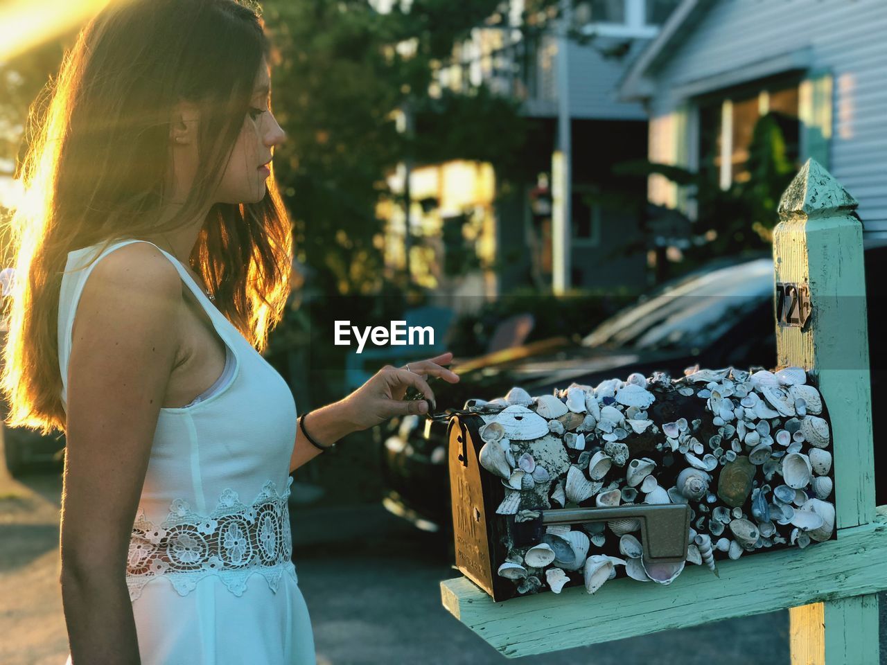 Side view of young woman opening mailbox