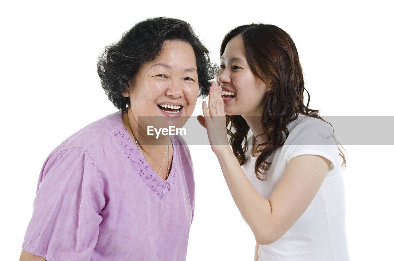 Portrait of smiling mature woman with daughter over white background