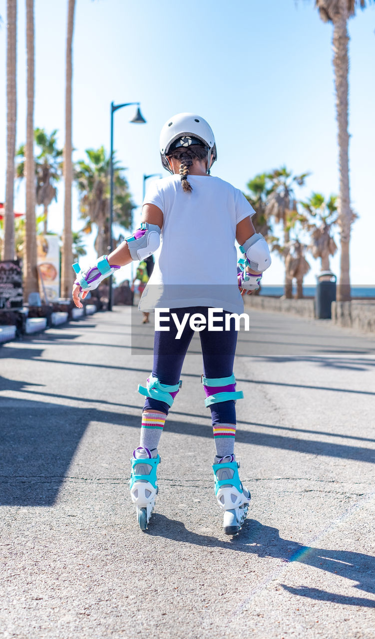 Rear view of girl inline skating on road