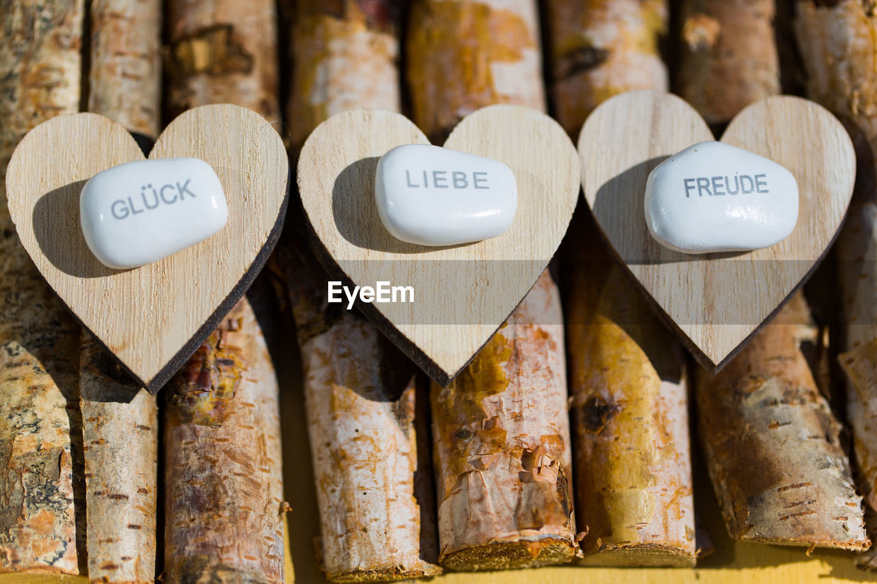 High angle view of soaps with text on heart shape wood over logs