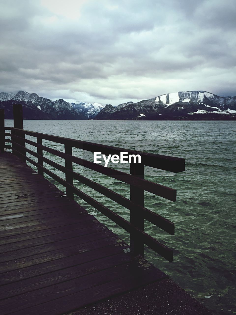 Wooden jetty on lake with mountains in background