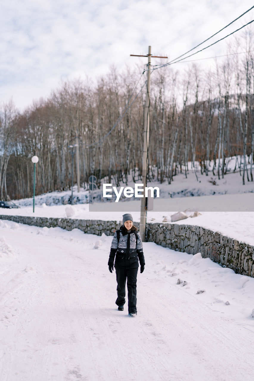 rear view of woman walking on snow covered field