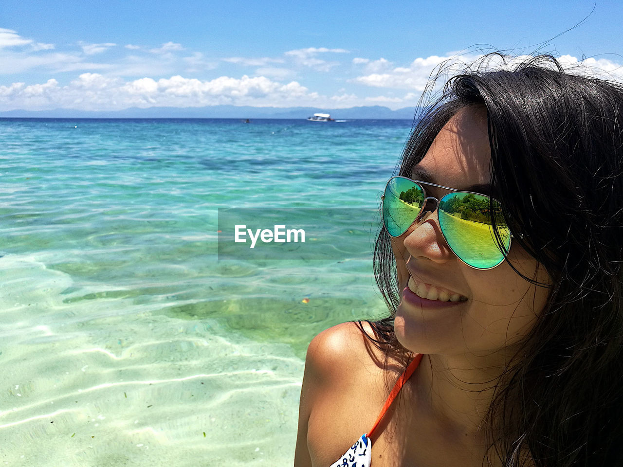 PORTRAIT OF YOUNG WOMAN IN SUNGLASSES AT BEACH