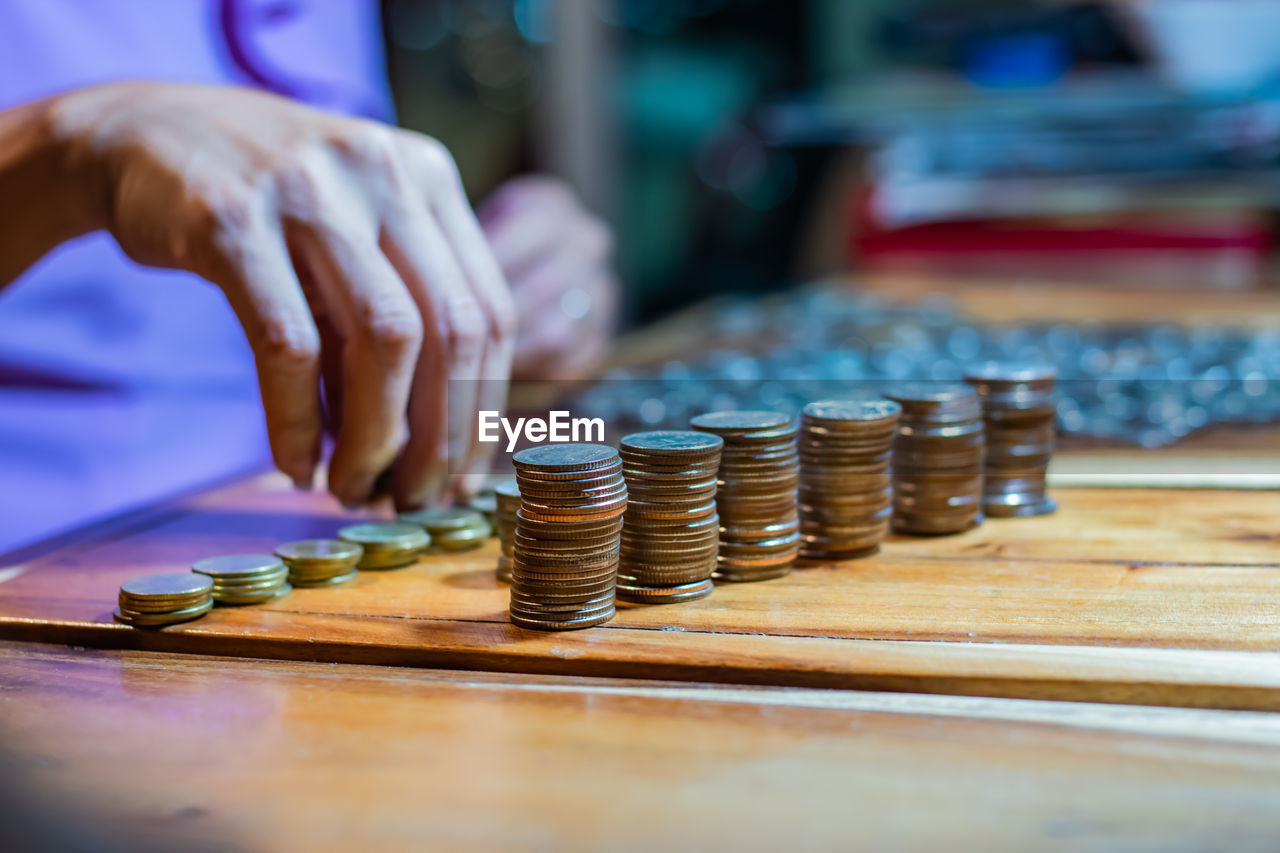 Midsection of woman counting coins while stacking on table