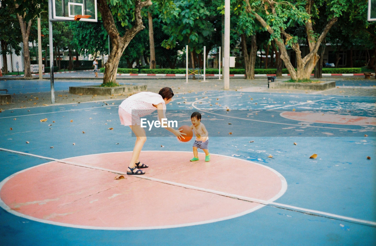 Mother and son playing basketball on court