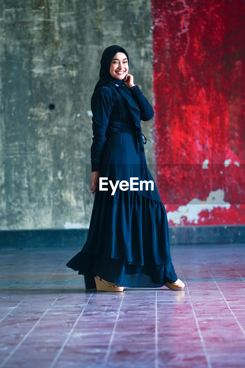 Beautiful indonesian woman wearing a black hijab against the rustic wall as a background