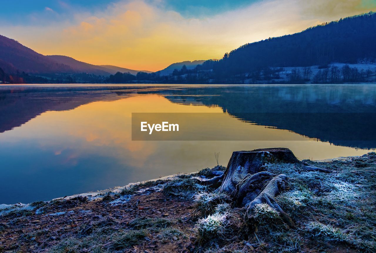 Scenic view of lake and mountains against sky during sunset