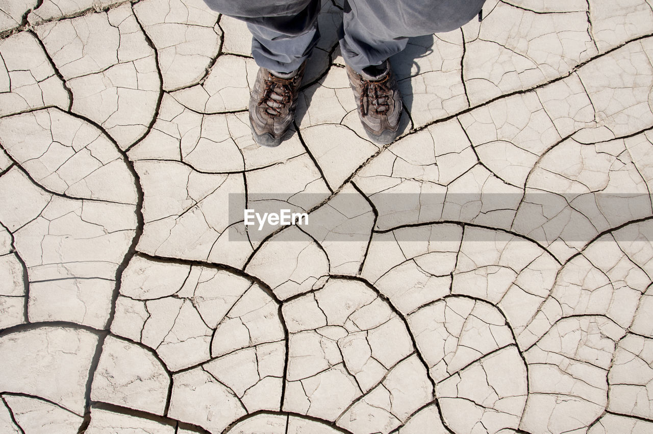 Low section of man standing on dried cracked soil during draught