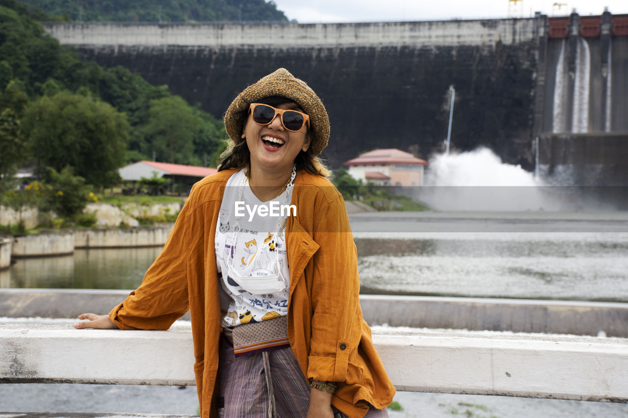 young woman standing against waterfall