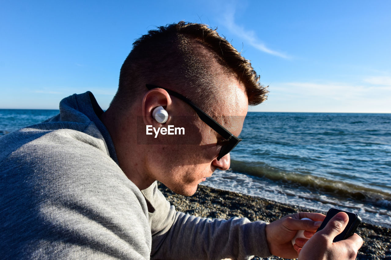 Close-up of man listening to music at beach