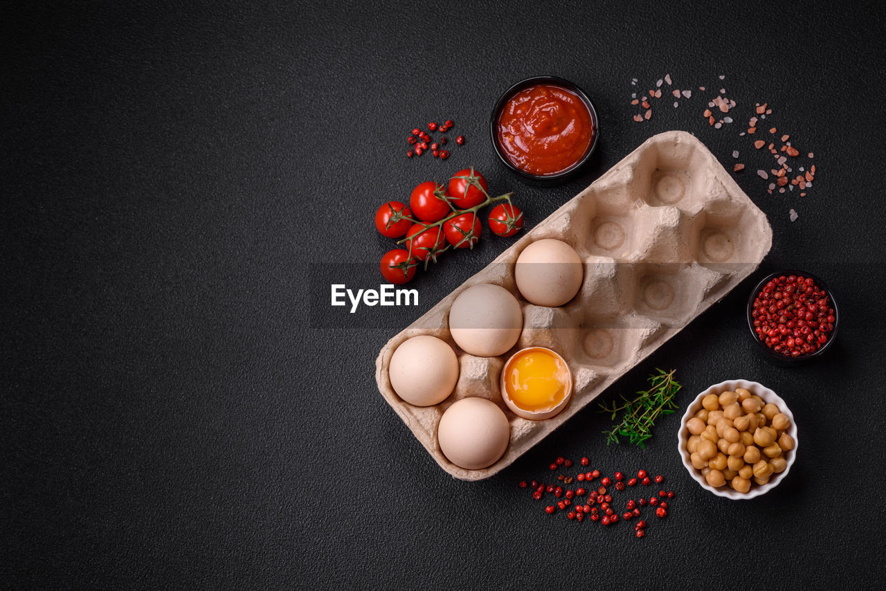 food and drink, food, healthy eating, egg, wellbeing, freshness, ingredient, studio shot, black background, indoors, no people, copy space, fruit, still life, raw food, spice, organic, high angle view, red, directly above, still life photography, table, meal, variation, breakfast, bowl, egg yolk, large group of objects