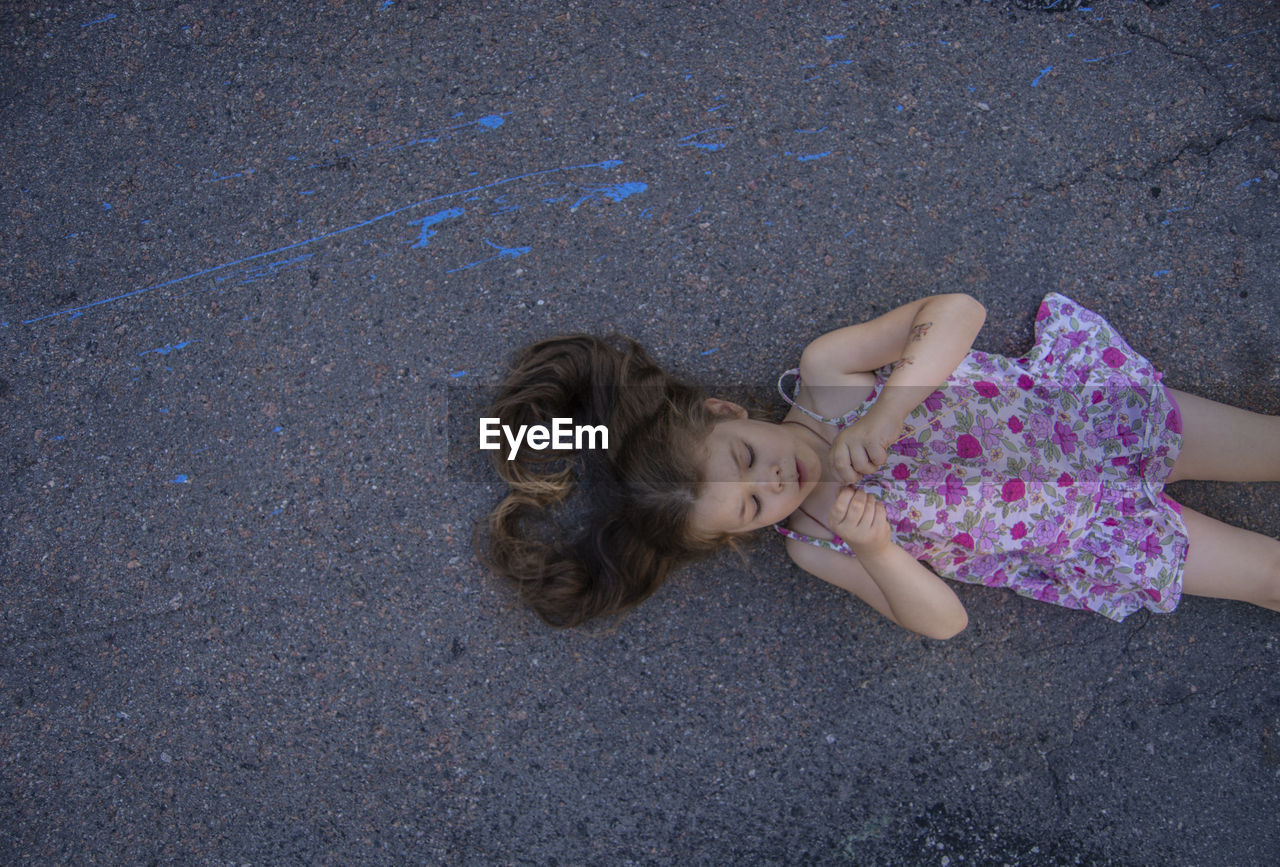 High angle view of girl lying down on road