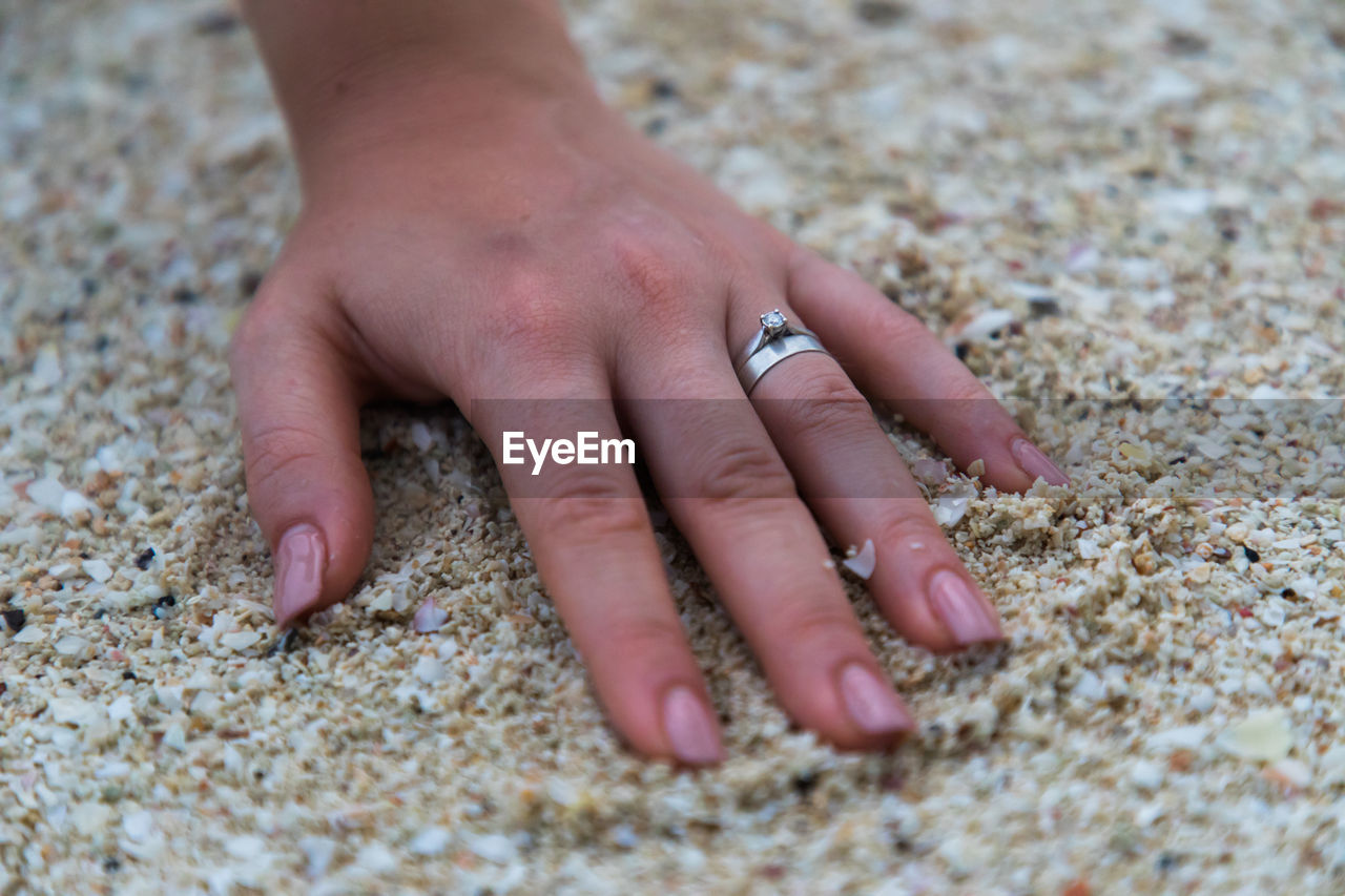 Close-up of hand touching sand