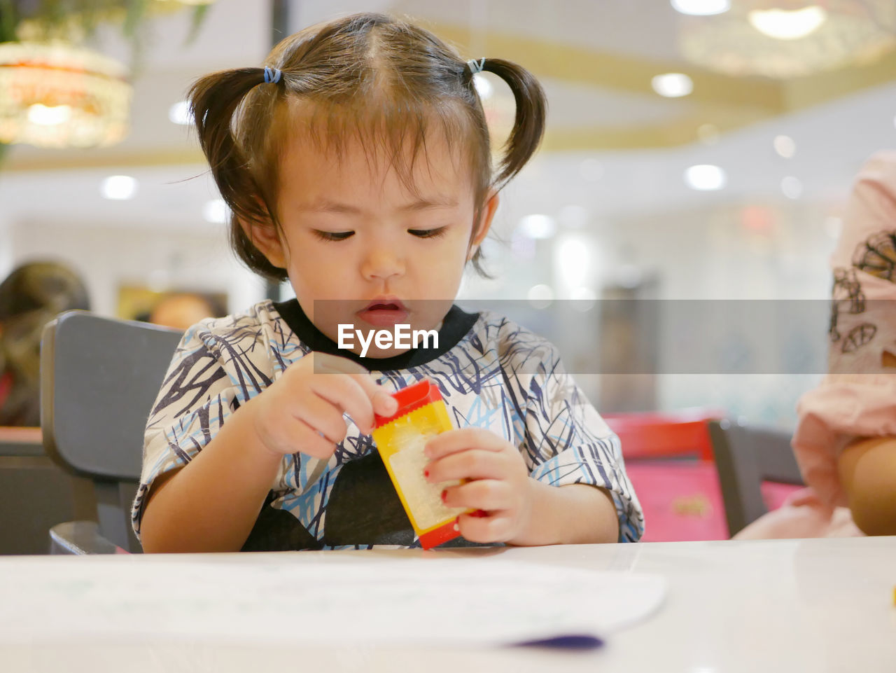 Cute baby girl coloring paper at table in restaurant