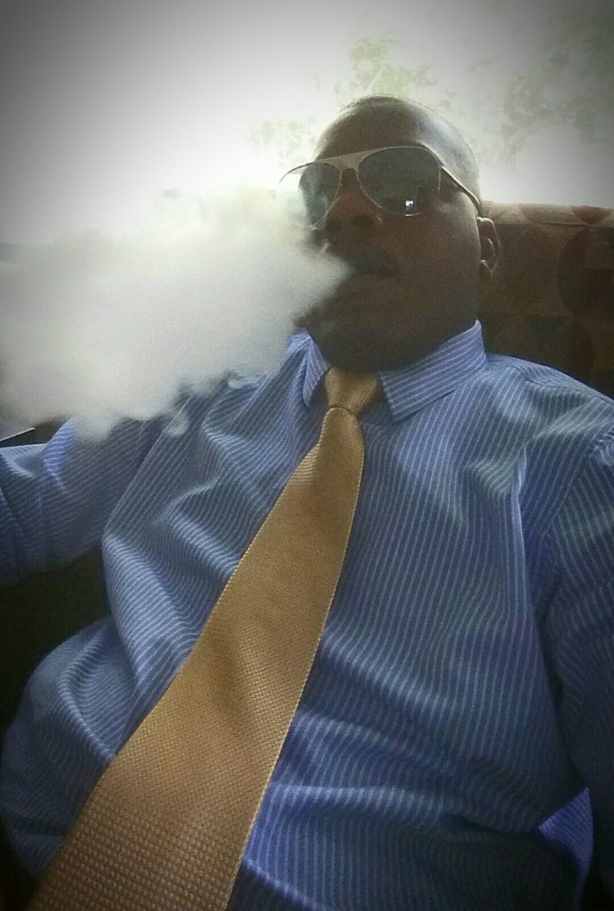 Low angle view of man smoking electronic cigarette at home