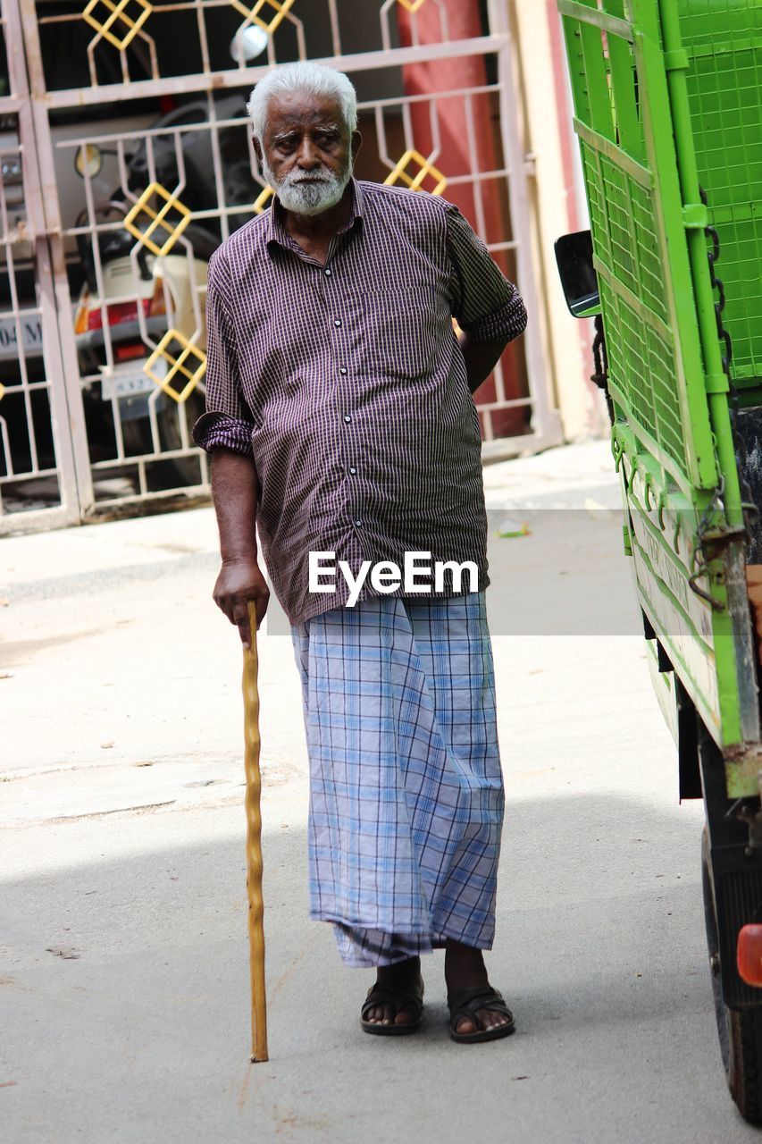 Senior man looking away while standing on street