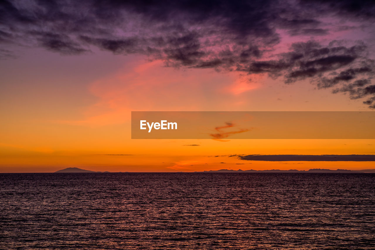 Scenic view of sea against dramatic sky during sunset