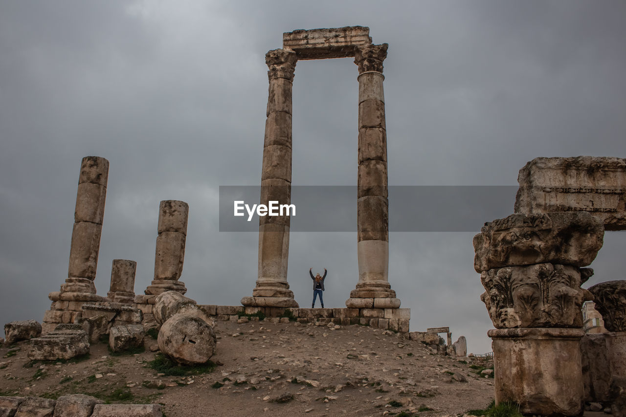 Woman with arms raised standing at temple of hercules