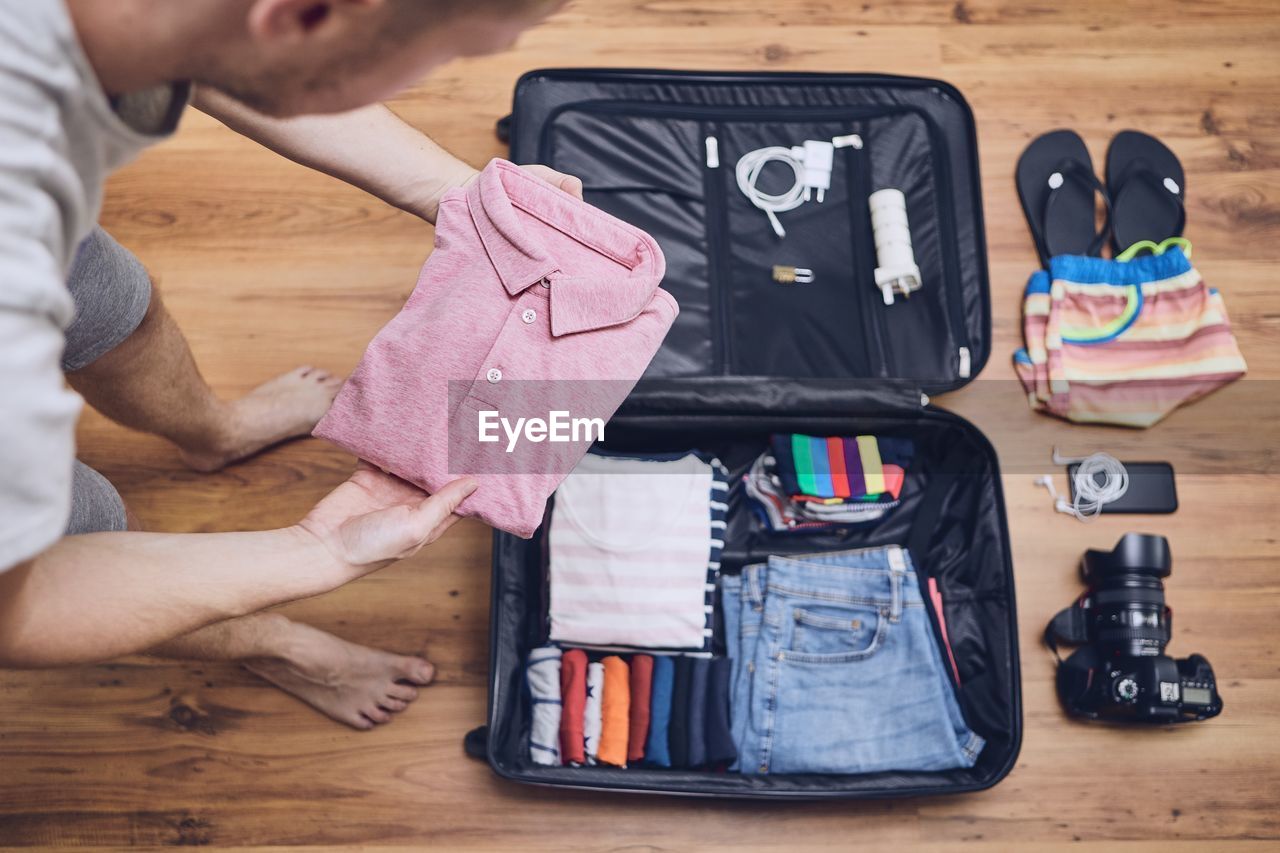 Man packing clothes in luggage at home