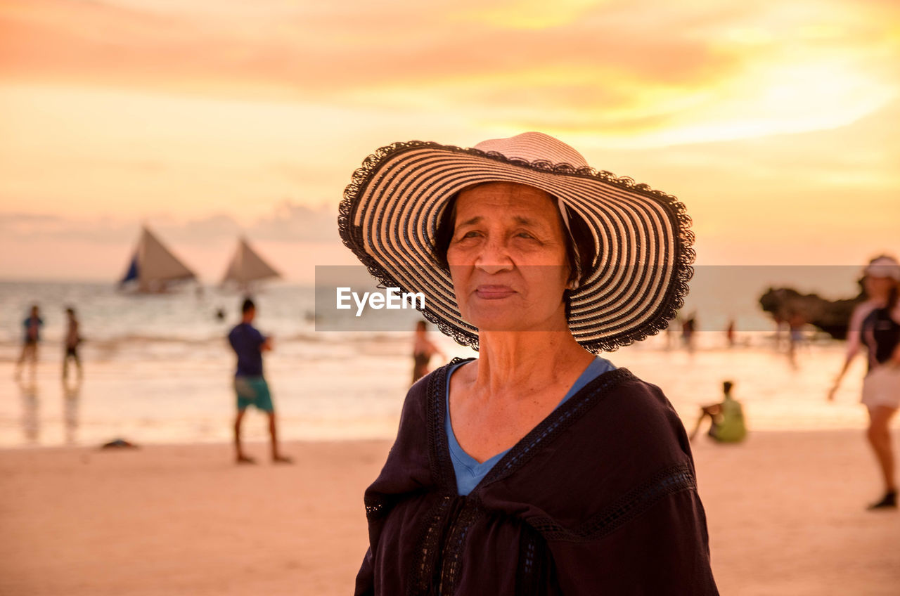 Portrait of woman on beach against sky during sunset