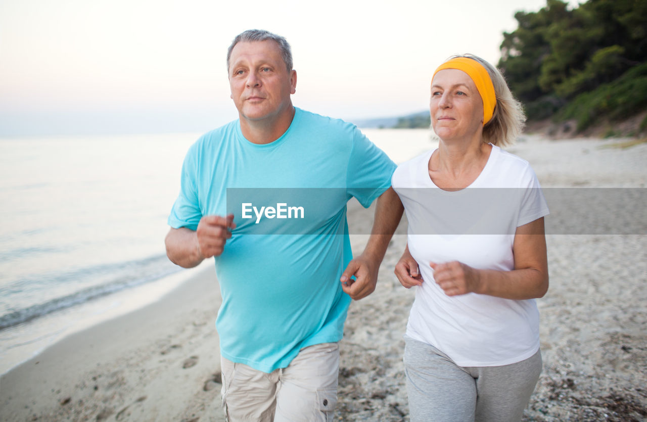 Mature couple jogging on shore at beach