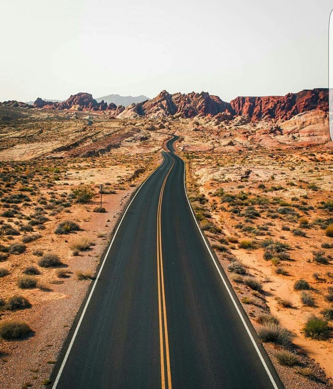 Empty road leading towards rocky mountains against sky