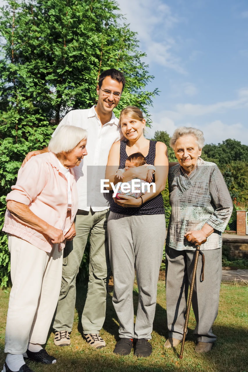 Portrait of happy family standing against trees and sky