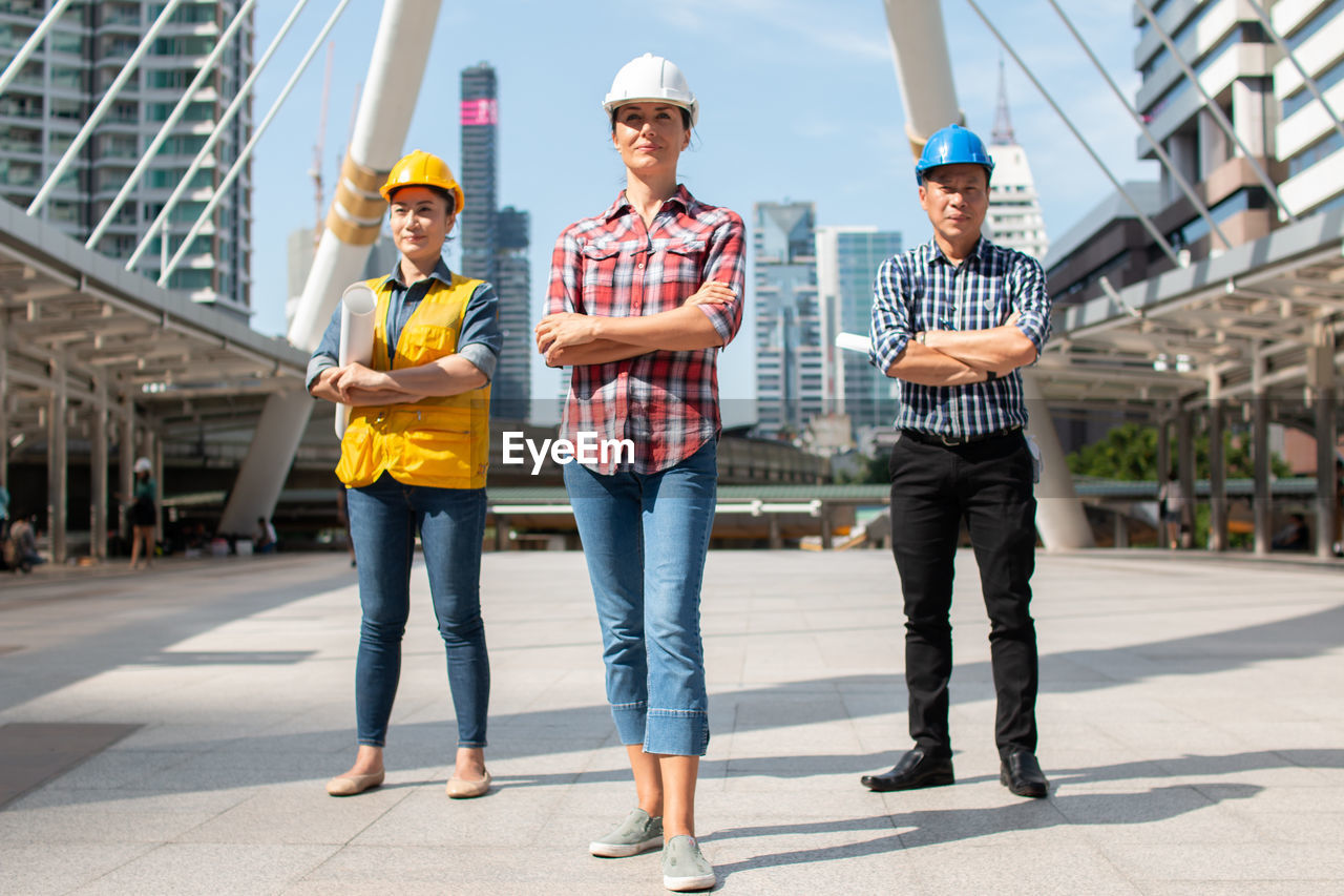 Full length of engineers standing in modern city