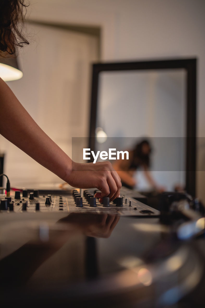 Cropped hand of woman playing sound mixer at home