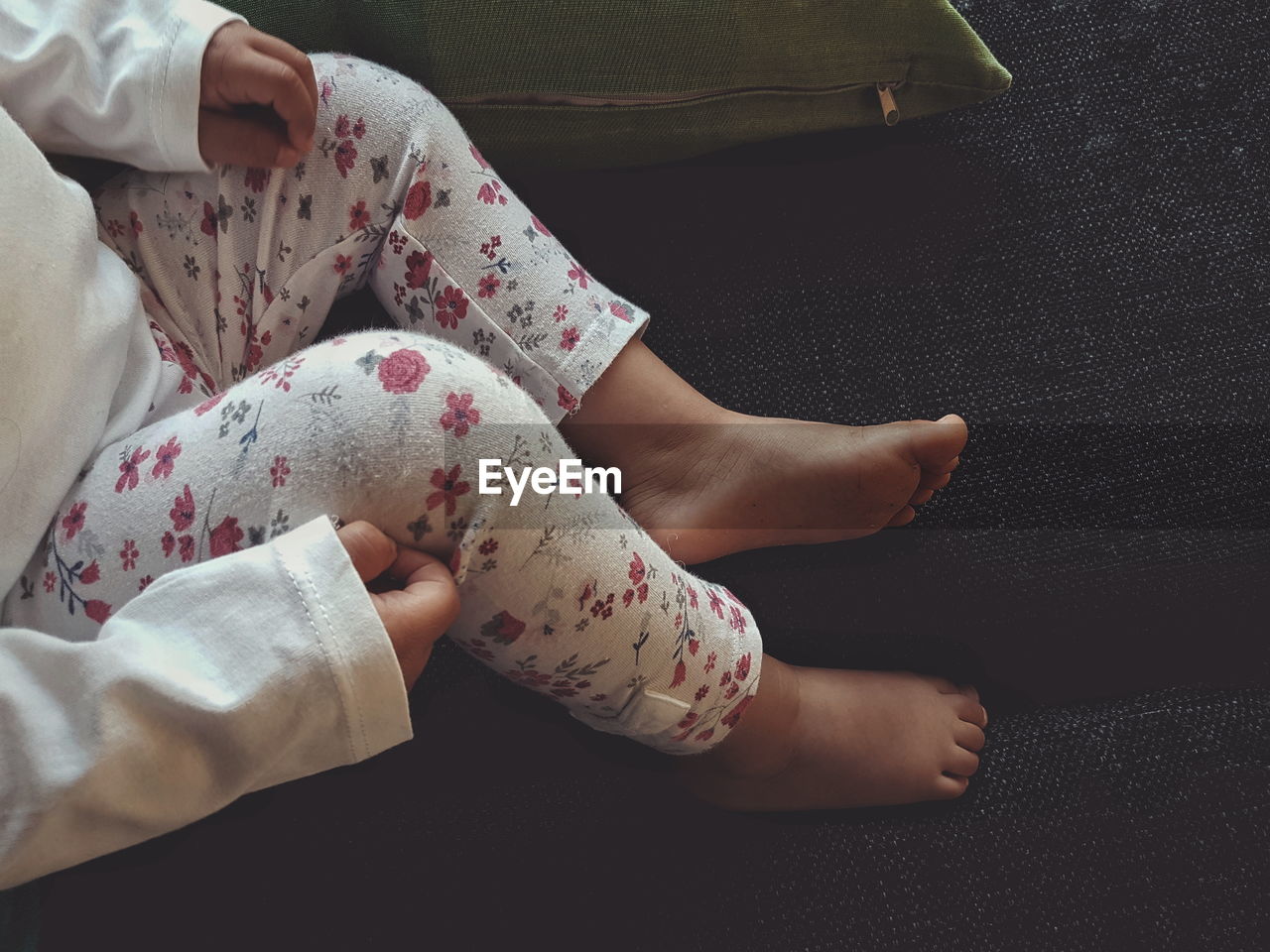 Low section of baby girl sitting on sofa at home