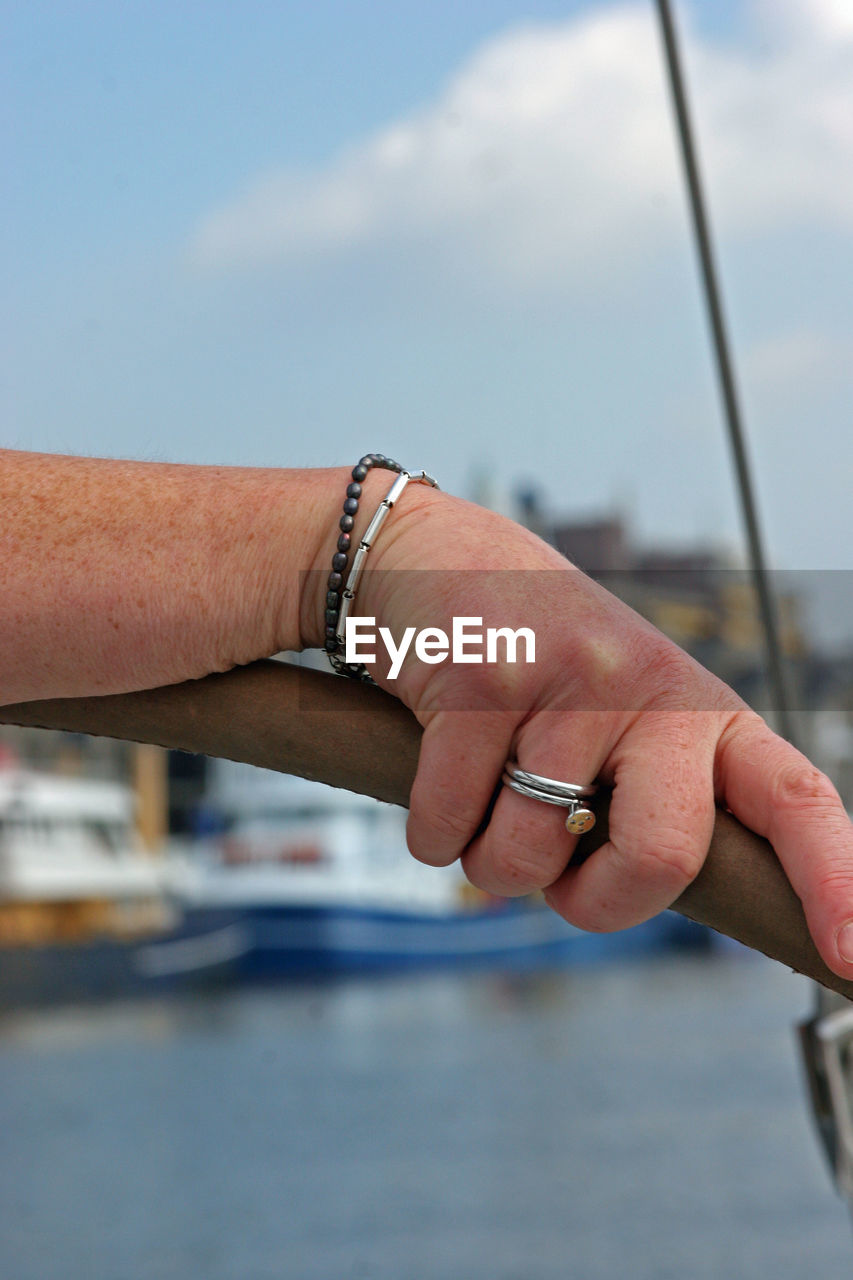 Cropped hand of woman holding railing against sea
