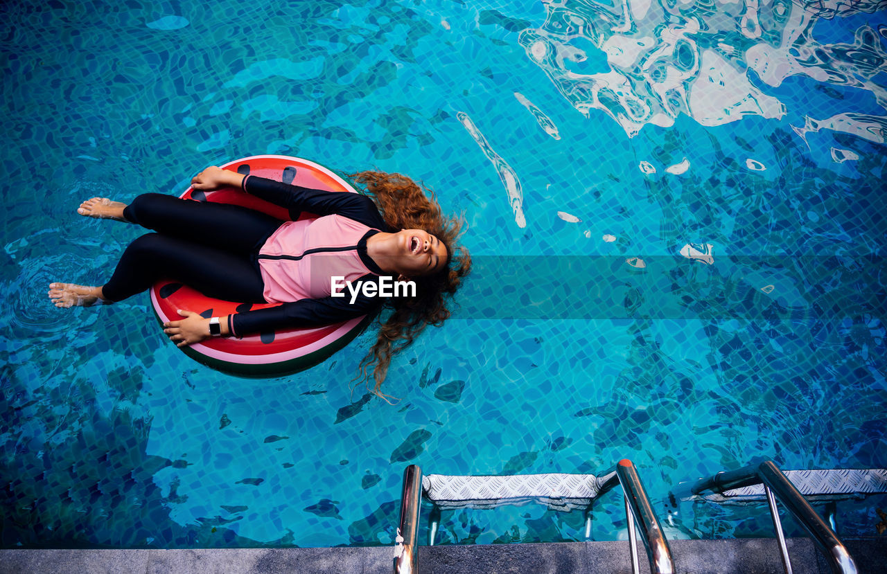 High angle view of girl floating on inflatable ring in swimming pool