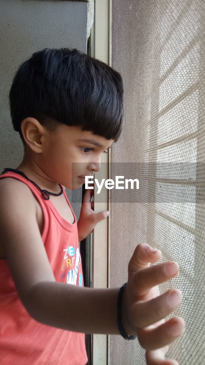 Boy looking through window at home