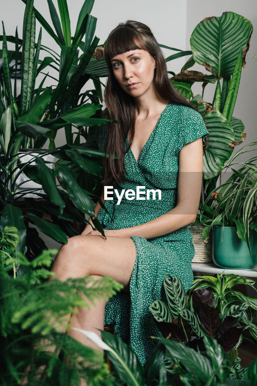 Portrait of woman sitting amidst plants