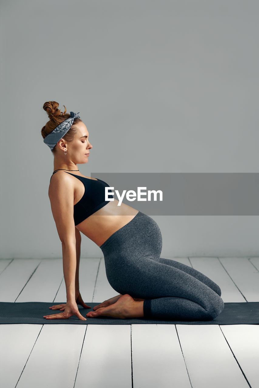 Side view of pregnant woman doing yoga at home