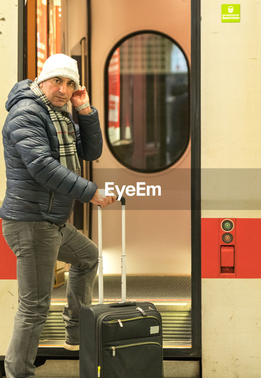 Portrait of man with luggage entering in train
