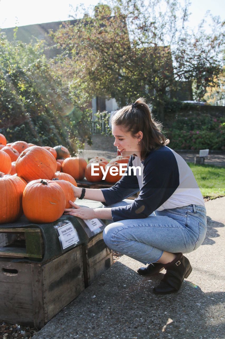 Side view full length of young woman holding pumpkin