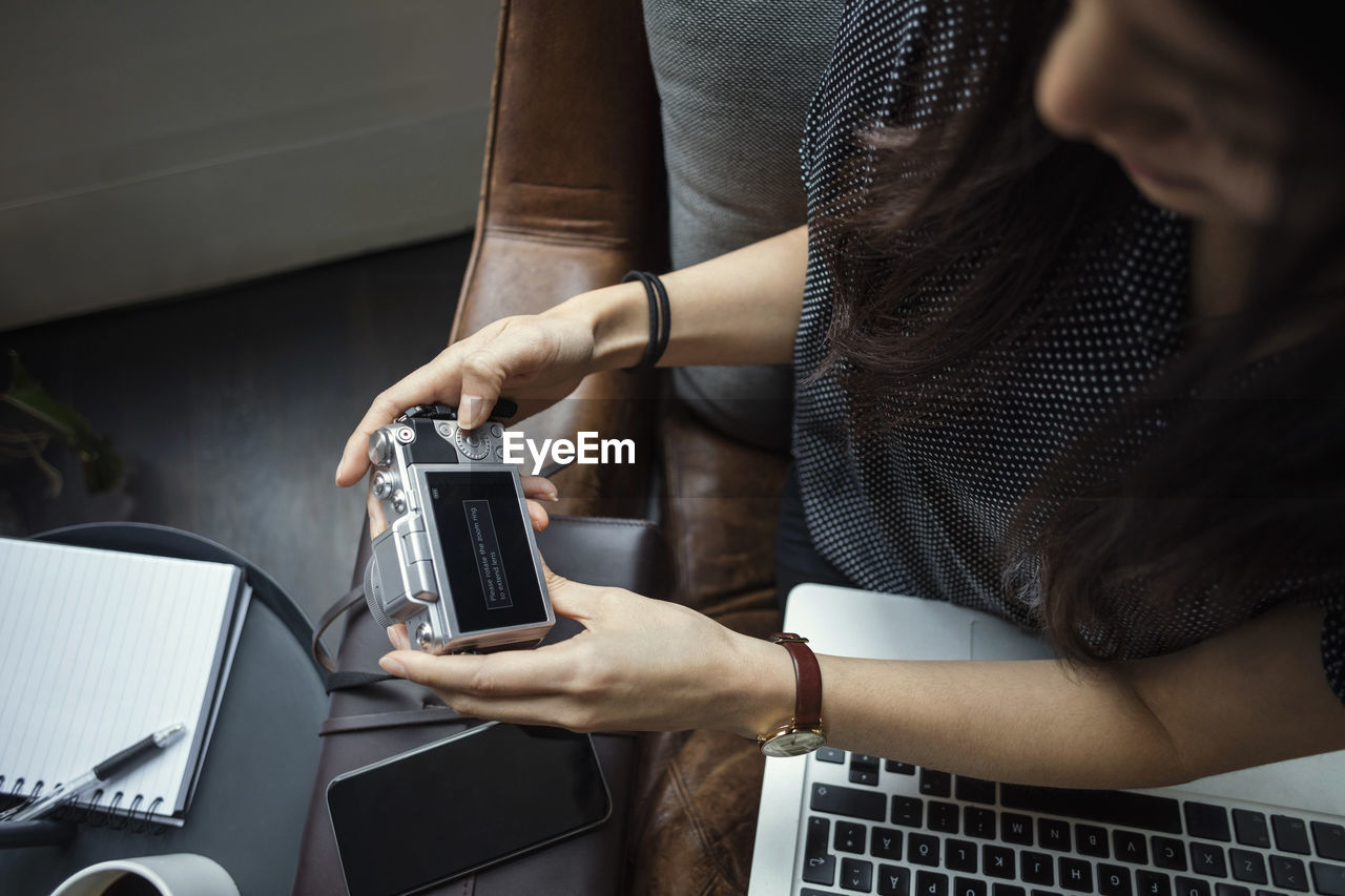 Cropped image of blogger using camera while sitting in office